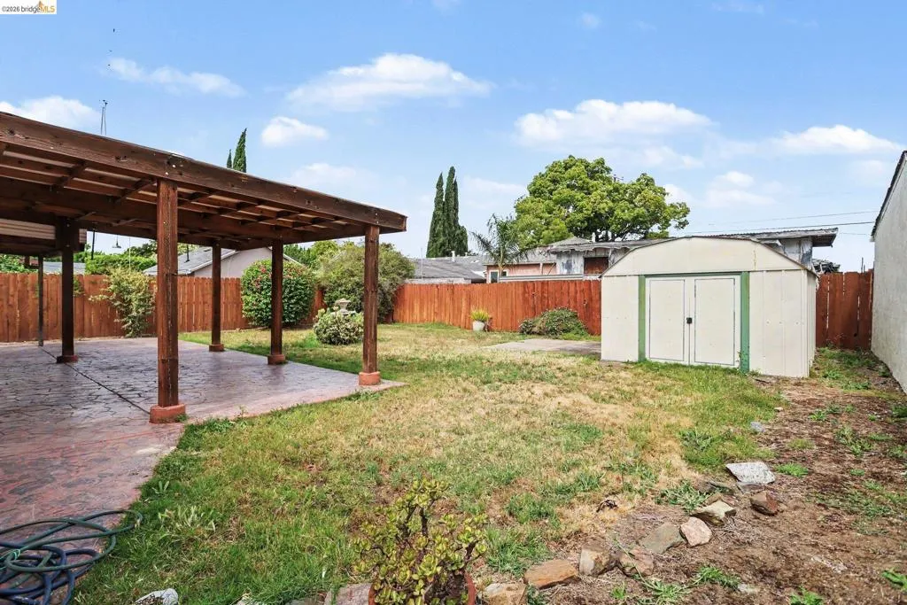 Expansive backyard with a covered patio featuring a wood beam pergola and a concrete patio