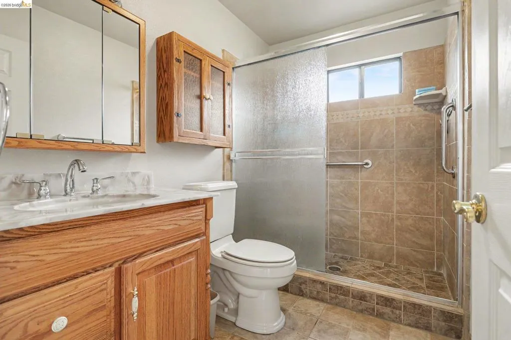 Bathroom featuring a wood-finish vanity with an integrated sink and a neutral stone-look countertop