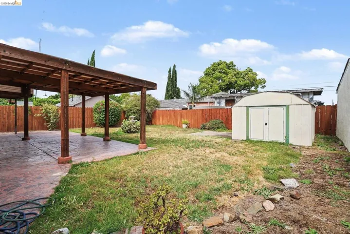 Expansive backyard with a covered patio featuring a wood beam pergola and a concrete patio
