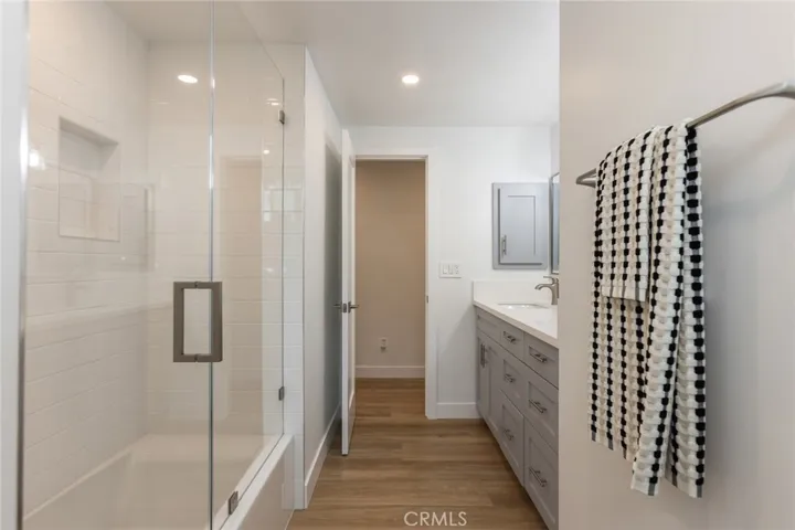 full shared bathroom with glass doors to bath tub