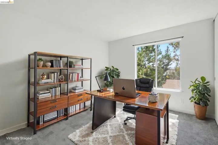 Bright room featuring a large window, light gray walls, and gray carpeting