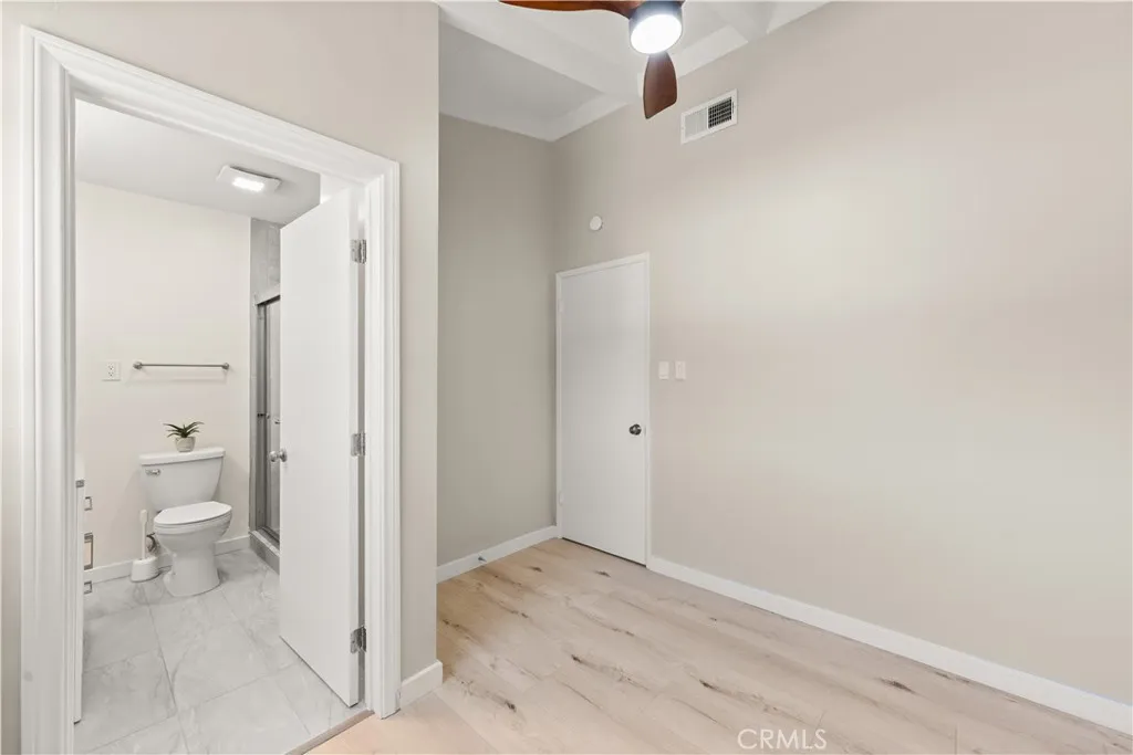 Bedroom with a private ensuite bath, featuring a step-in shower and custom glass doors.
