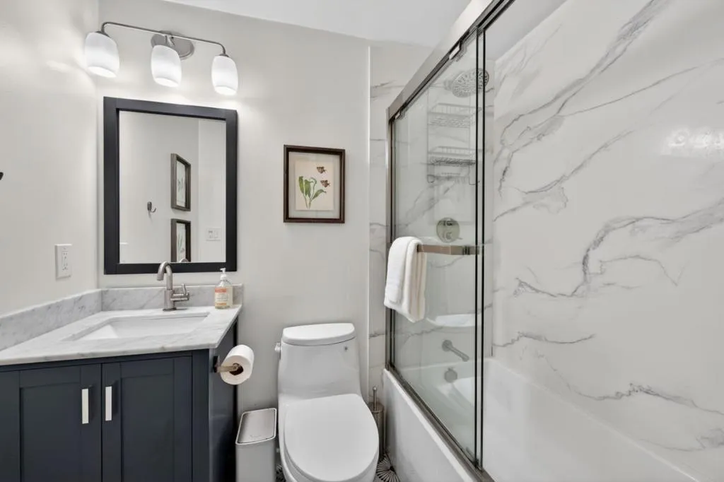Solid surface shower walls with a shower over the tub.