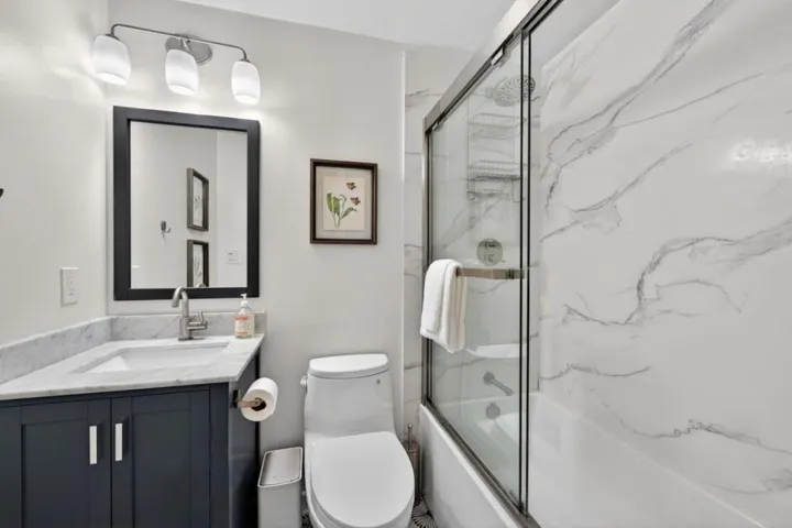 Solid surface shower walls with a shower over the tub.