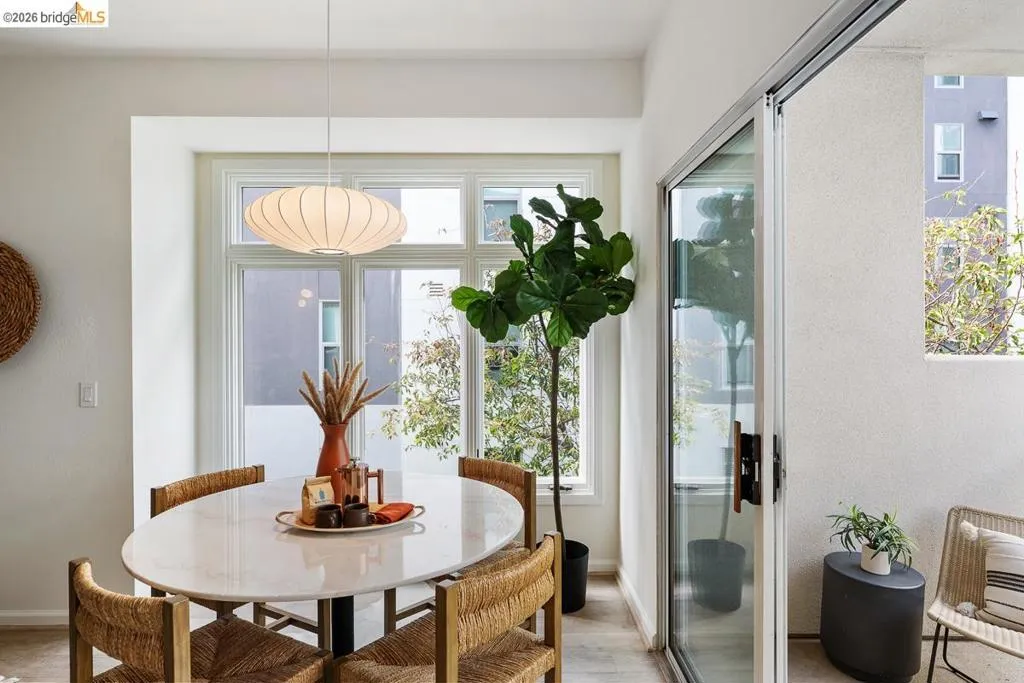 Dining area featuring a contemporary pendant light fixture, large multi-pane window, and light wood-finish flooring Dining area featuring a contemporary pendant light fixture, large multi-pane window, and light wood-finish flooring