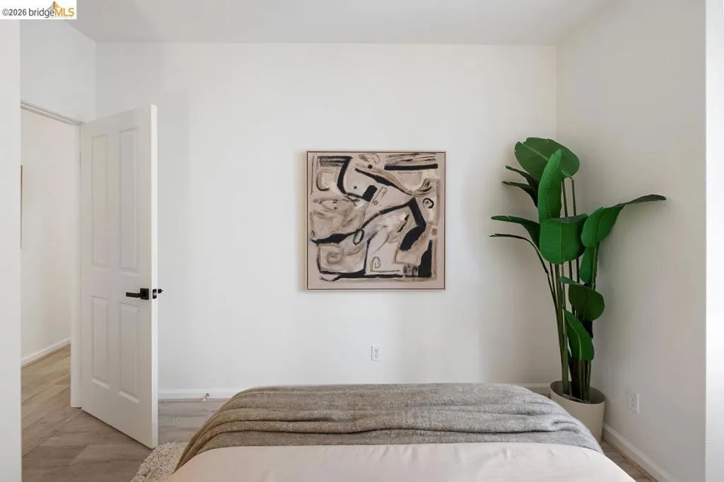 Bedroom featuring light-colored walls and wood-finish flooring Bedroom featuring light-colored walls and wood-finish flooring