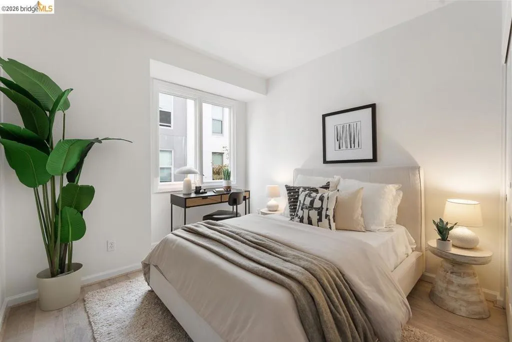 Light wood-finish flooring and white walls define this bedroom space Light wood-finish flooring and white walls define this bedroom space