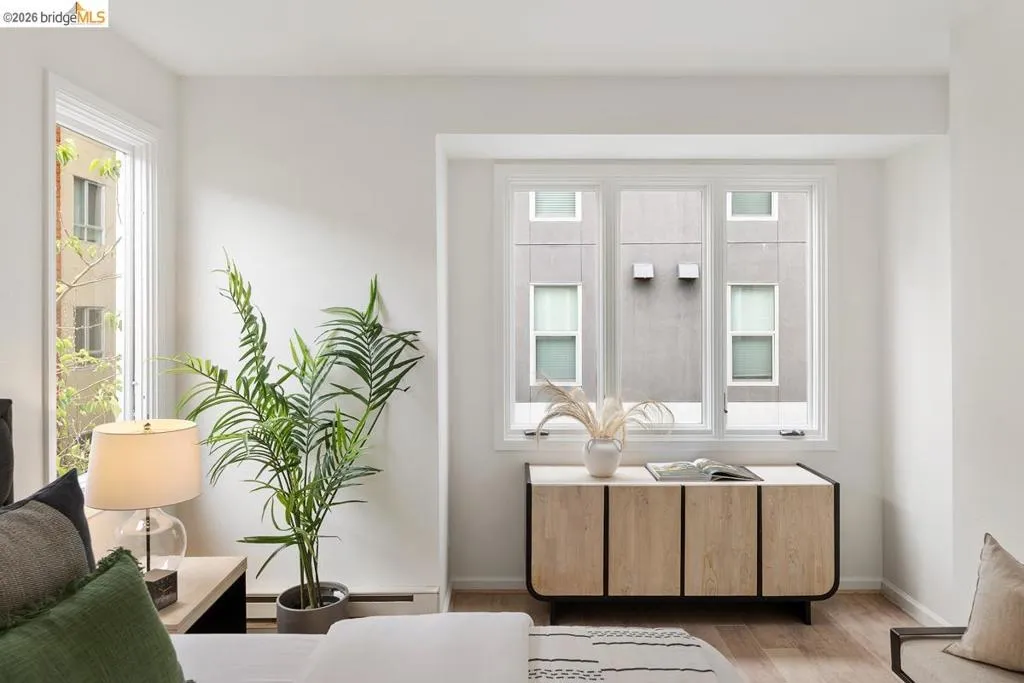Bright interior featuring multiple windows, white trim, and wood-finish flooring Bright interior featuring multiple windows, white trim, and wood-finish flooring
