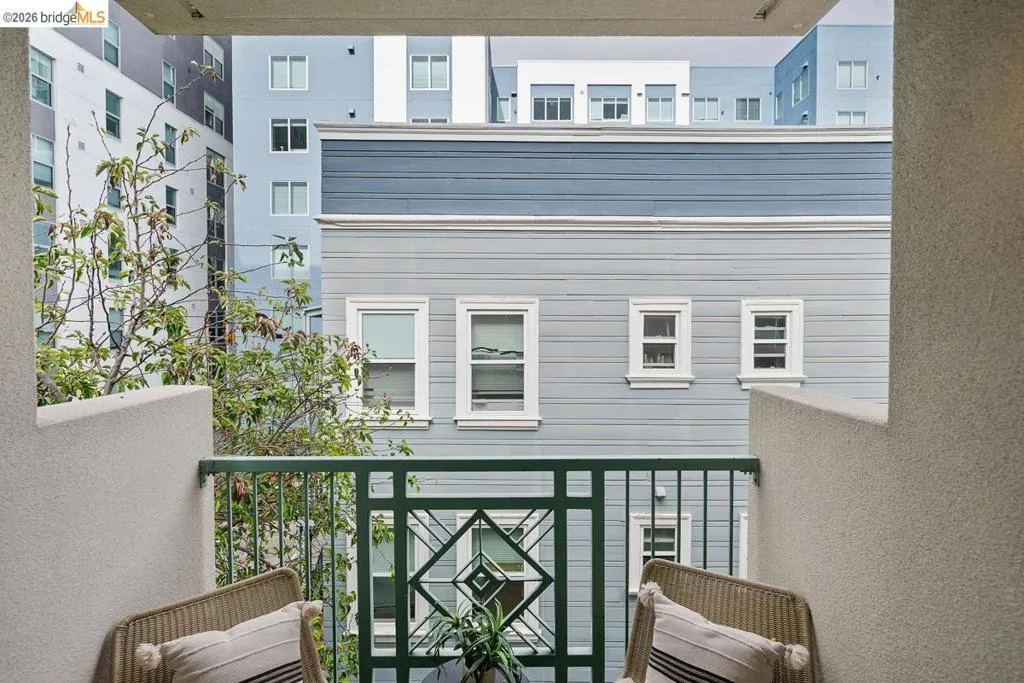Balcony with a dark green metal railing featuring a geometric design, framed by textured light-colored stucco walls Balcony with a dark green metal railing featuring a geometric design, framed by textured light-colored stucco walls