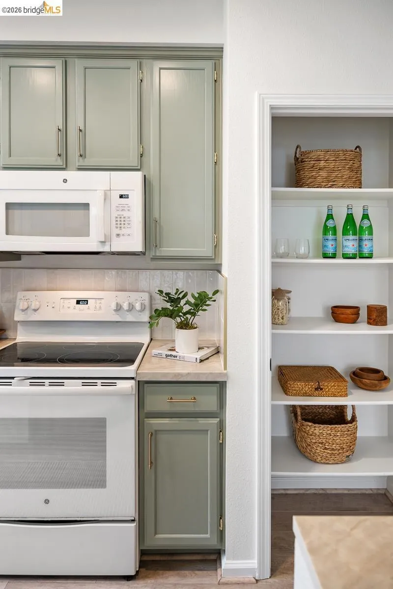 Kitchen featuring sage green cabinetry, white appliances, and a built-in microwave Kitchen featuring sage green cabinetry, white appliances, and a built-in microwave
