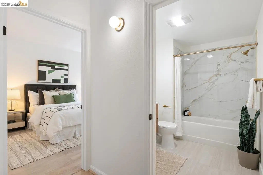 Well-appointed bathroom featuring a tub/shower combination with a gold-tone showerhead, a white marble-patterned surround, and gold-tone fixtures Well-appointed bathroom featuring a tub/shower combination with a gold-tone showerhead, a white marble-patterned surround, and gold-tone fixtures