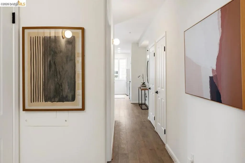 Hallway with wood-finish flooring and white walls Hallway with wood-finish flooring and white walls