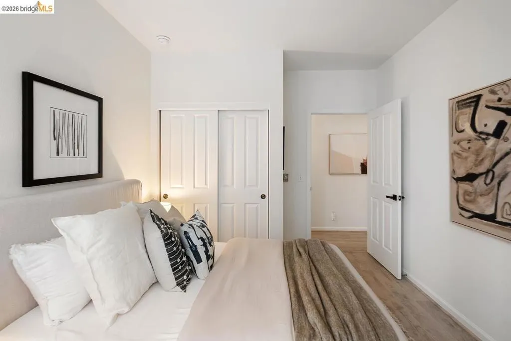 Bedroom featuring light wood-finish flooring, white walls, and a closet with white bi-fold doors Bedroom featuring light wood-finish flooring, white walls, and a closet with white bi-fold doors