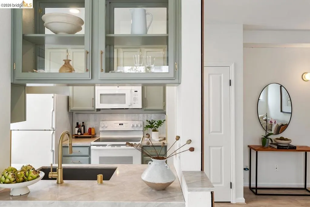 Kitchen featuring light green cabinetry with glass-front uppers, a built-in microwave, and a white electric range Kitchen featuring light green cabinetry with glass-front uppers, a built-in microwave, and a white electric range