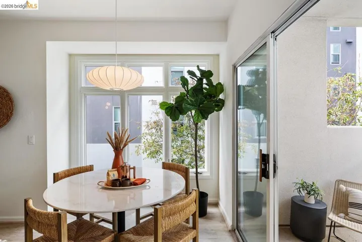 Dining area featuring a contemporary pendant light fixture, large multi-pane window, and light wood-finish flooring