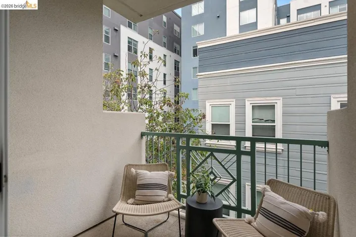 Private balcony featuring a textured stucco wall and decorative metal railing
