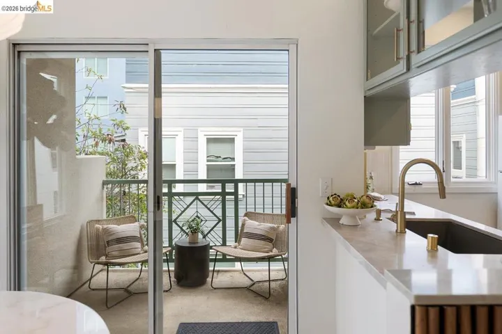 Balcony with sliding glass door access, featuring a decorative metal railing and concrete flooring