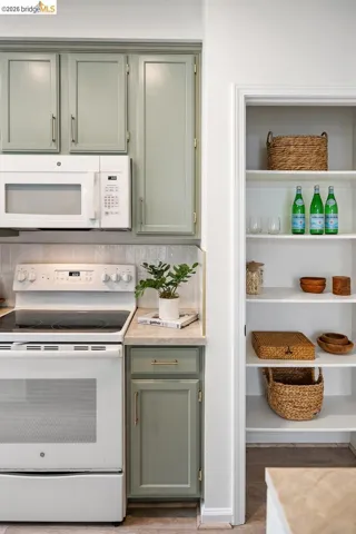 Kitchen featuring sage green cabinetry, white appliances, and a built-in microwave