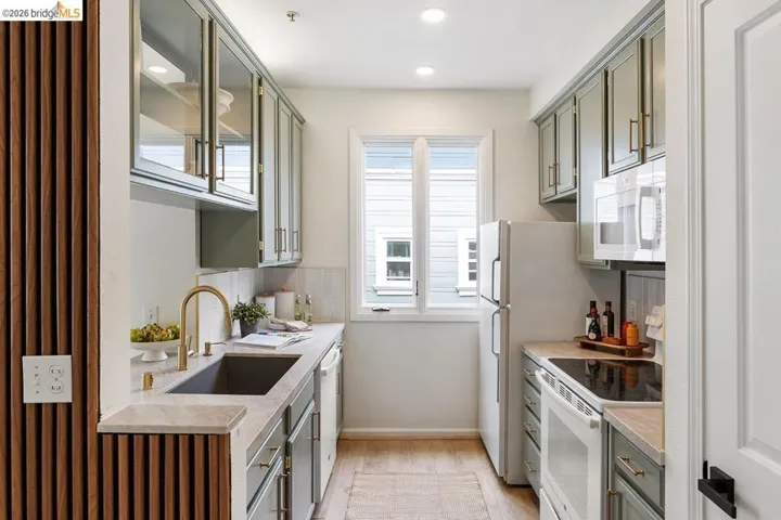Galley kitchen featuring light green cabinetry, a single window, recessed lighting, and wood-finish flooring