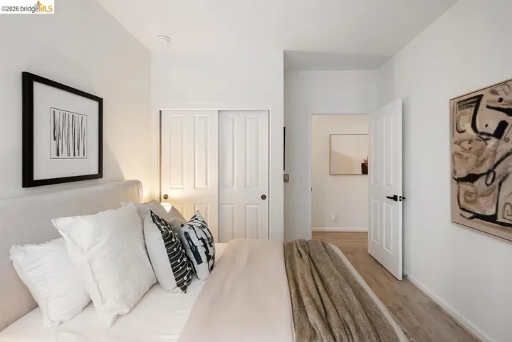 Bedroom featuring light wood-finish flooring, white walls, and a closet with white bi-fold doors