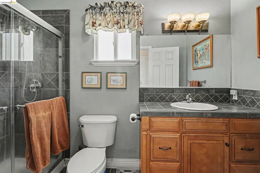 Bathroom featuring a shower with dark grey tile surround and glass enclosure