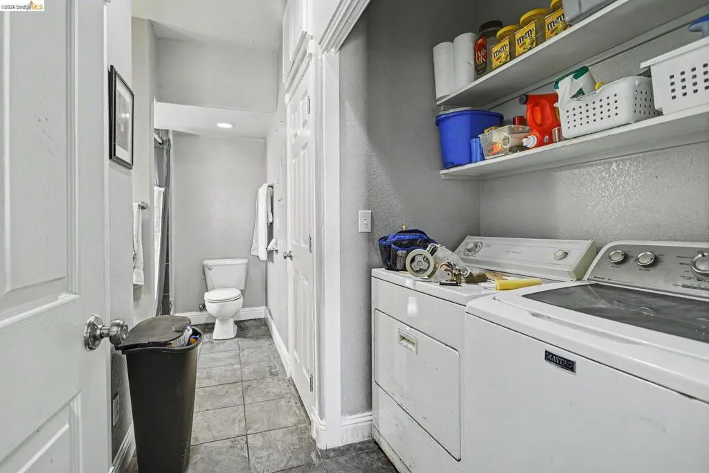 Dedicated laundry area featuring a washer and dryer, accompanied by a full bathroom with a toilet and shower