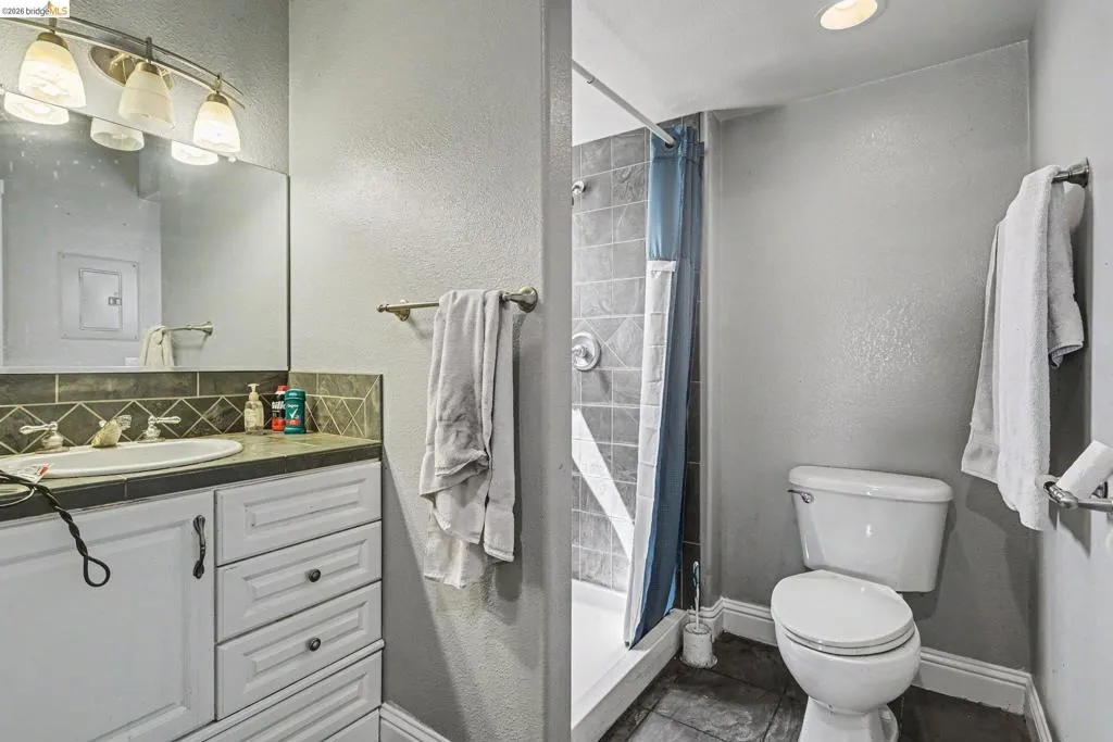 Bathroom featuring a vanity with a white basin, dark countertop, and tiled backsplash