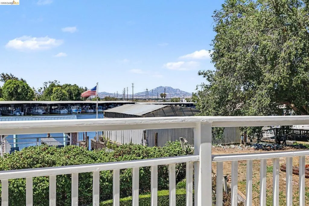 Waterfront scenery featuring a boat dock with multiple vessels, a distant mountain range, and mature trees framing the property