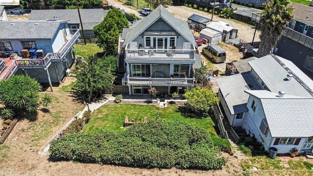 Three-story residence featuring multiple balconies, a gabled roofline, and a manicured lawn area
