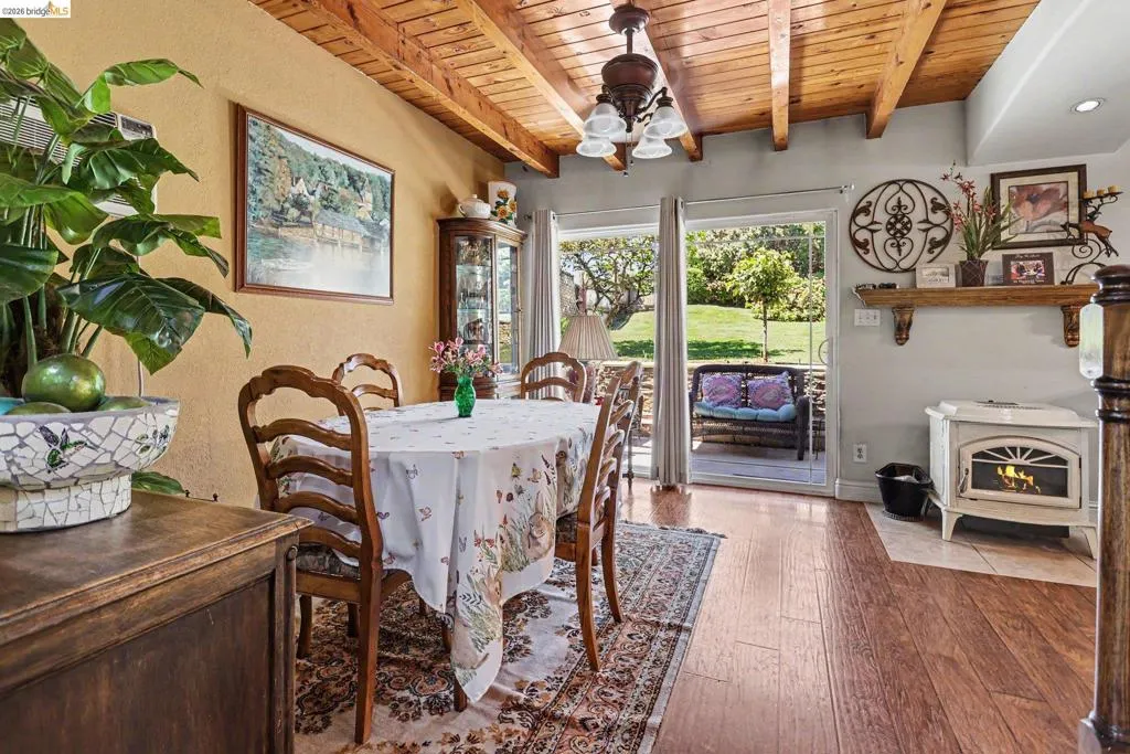 Dining area featuring a wood-beam ceiling, wood-finish flooring, and white stove