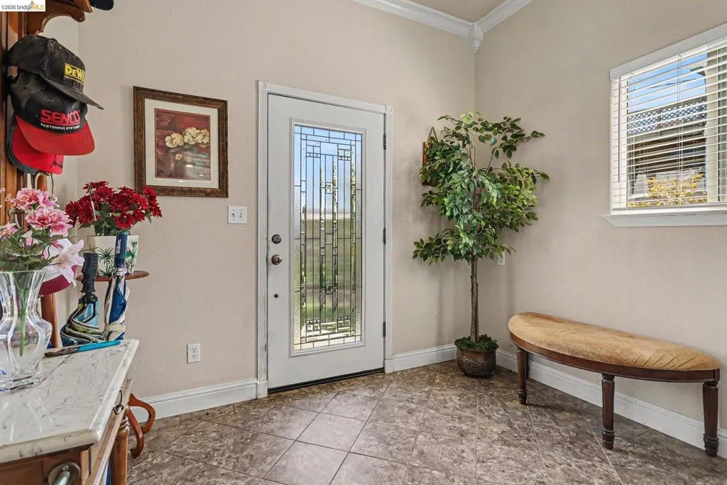 Entryway featuring tiled flooring, a white door with decorative glass inserts, and a window with blinds