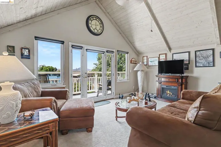 Vaulted wood-paneled ceiling accenting a bright living space with carpet flooring