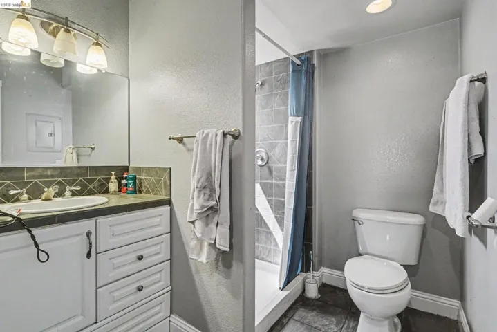 Bathroom featuring a vanity with a white basin, dark countertop, and tiled backsplash
