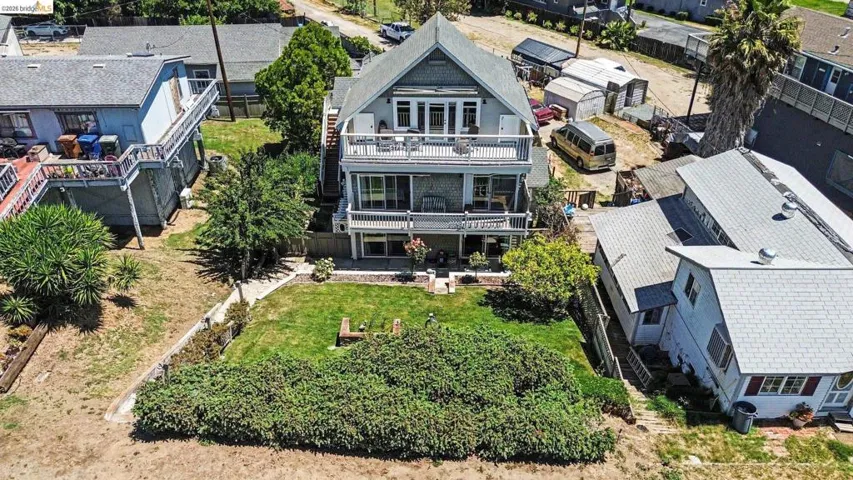 Three-story residence featuring multiple balconies, a gabled roofline, and a manicured lawn area