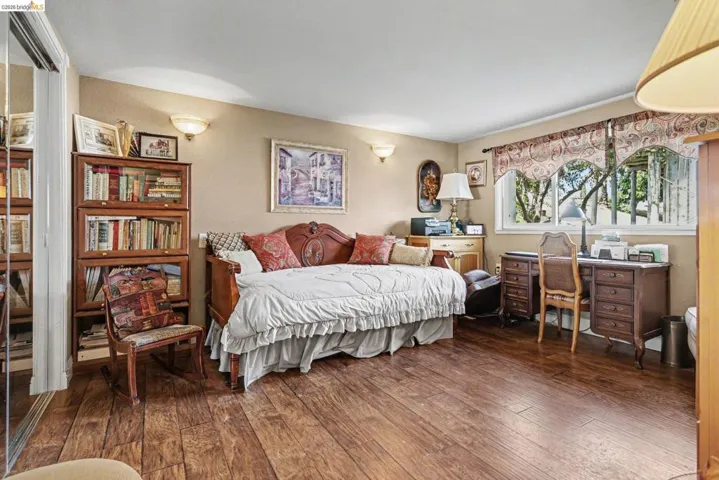 Spacious room featuring wood-finish flooring, a large window with exterior foliage, and ample natural light