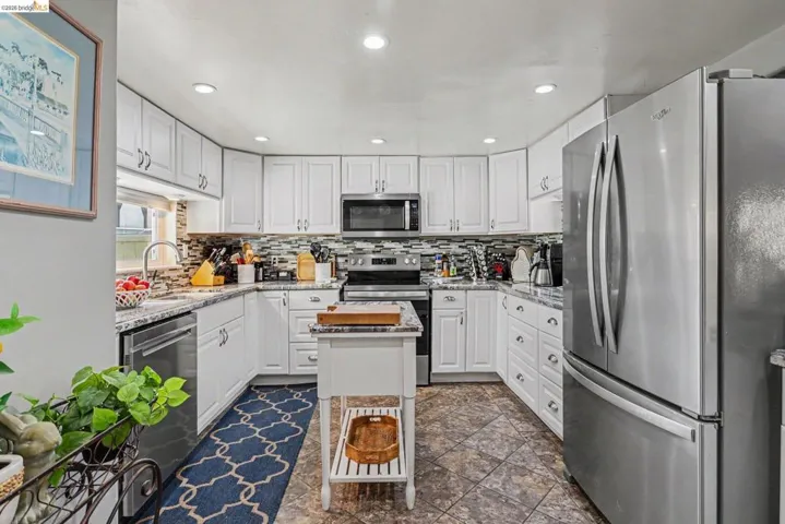 Kitchen featuring white cabinetry, stainless steel appliances, recessed lighting, a mosaic tile backsplash, and stone-finish countertops