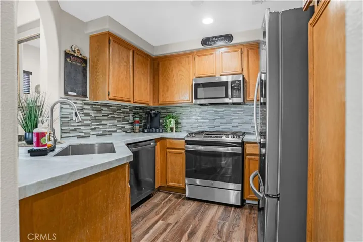 KITCHEN FEATURING QUARTZ COUNTERTOPS, A NEUTRAL GLASS TIILE BACKSPLASH, AND STAINLESS-STEEL APPLIANCES.
