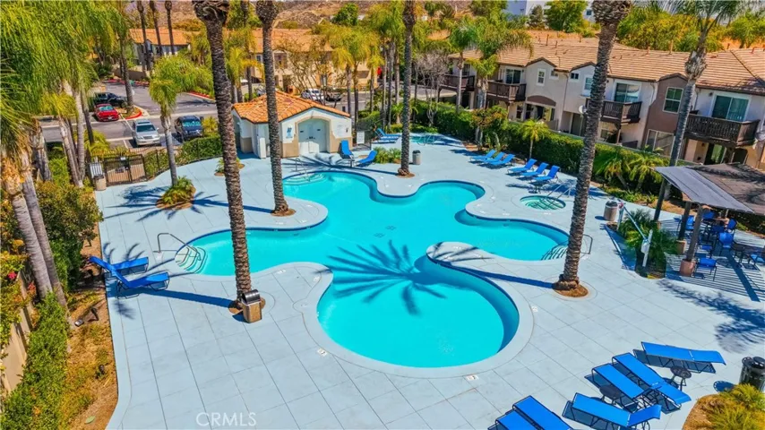 RECENTLY RENOVATED RESORT-STYLE COMMUNITY POOL FEATURING NEW LOUNGE CHAIRS, AND A BEAUTIFUL PALM-LINED SETTING.