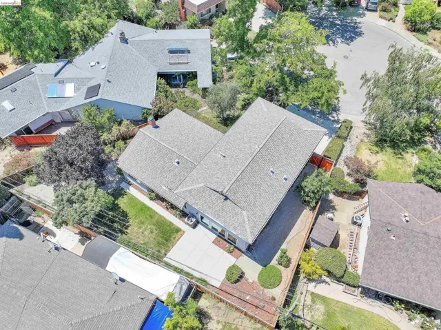 Aerial perspective showcasing a property with a grey shingle roof and a concrete patio