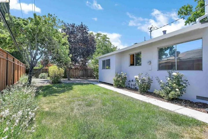 Expansive backyard featuring a lush lawn, mature trees, and a wooden perimeter fence