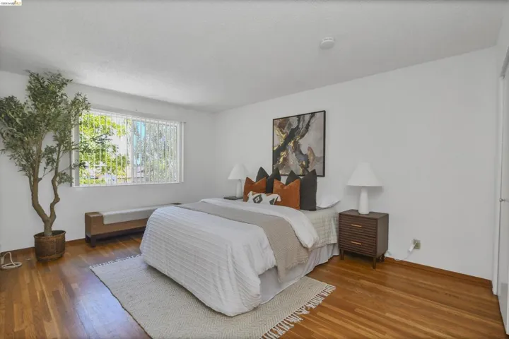 Spacious room featuring wood-finish flooring, a large window with vertical blinds, and a neutral color palette