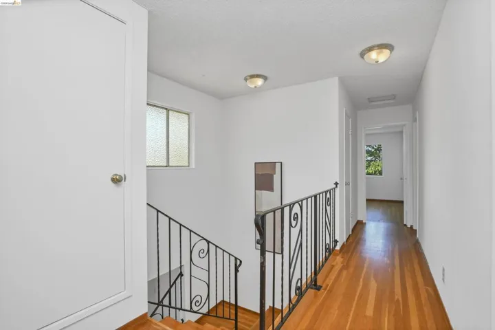 Upper-level hallway featuring wood-finish flooring, white walls, and flush-mount lighting