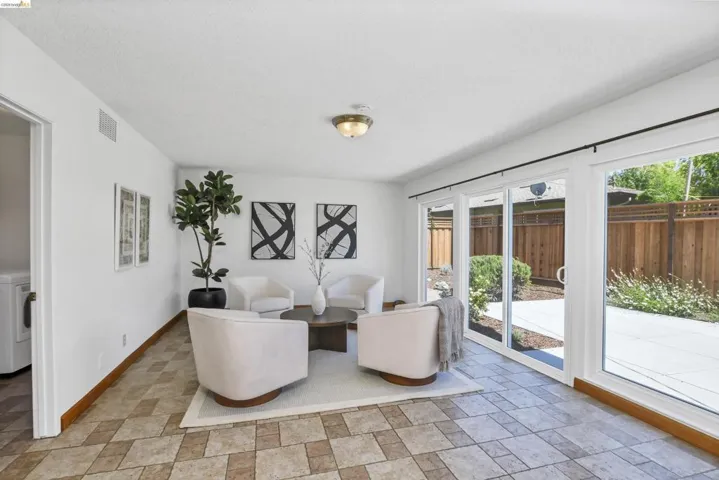 Sunlit interior space featuring tile flooring and sliding glass doors opening to an outdoor patio with wood fencing