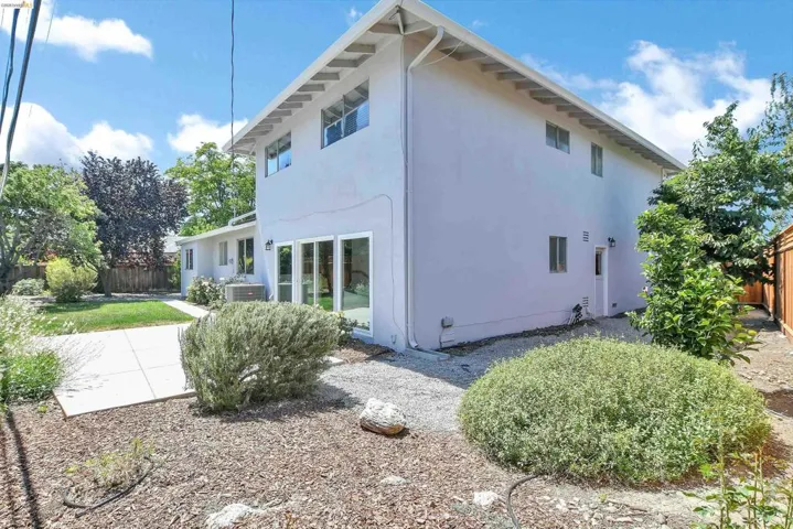 Rear exterior featuring a stucco facade, multiple windows, and a paved patio area