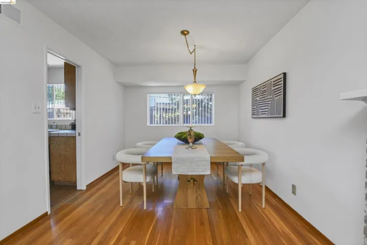 Bright dining area featuring wood-finish flooring and a central window with vertical blinds