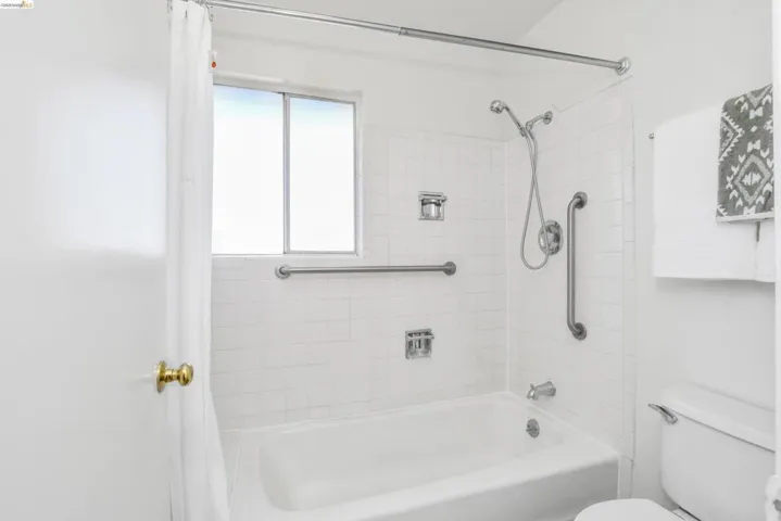 White tiled tub and shower combination with chrome fixtures