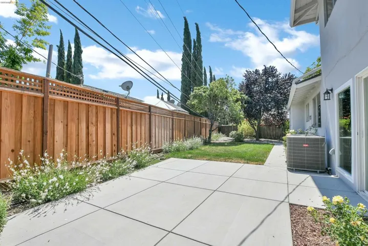 Expansive concrete patio with geometric scoring, bordered by a wooden fence with lattice detailing