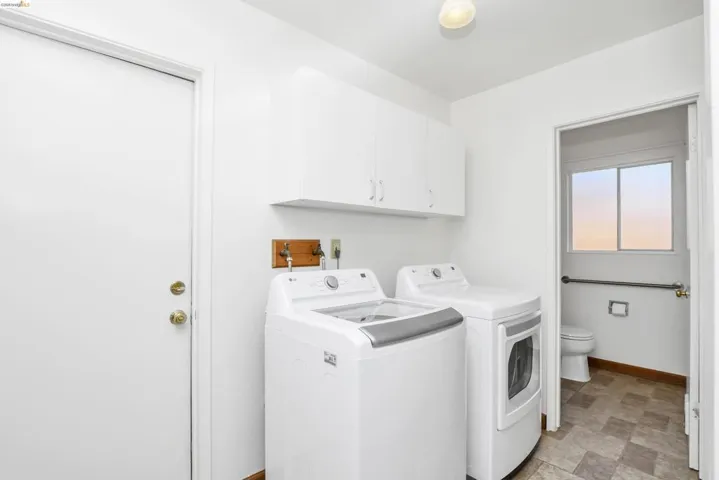 Dedicated laundry area featuring upper white cabinetry, a white washer, and a white dryer