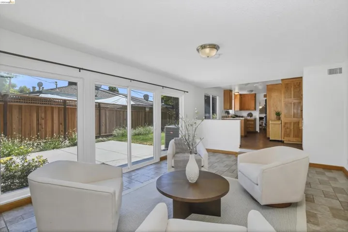 Living area with tile flooring and white walls, featuring multiple glass sliding doors providing direct patio access