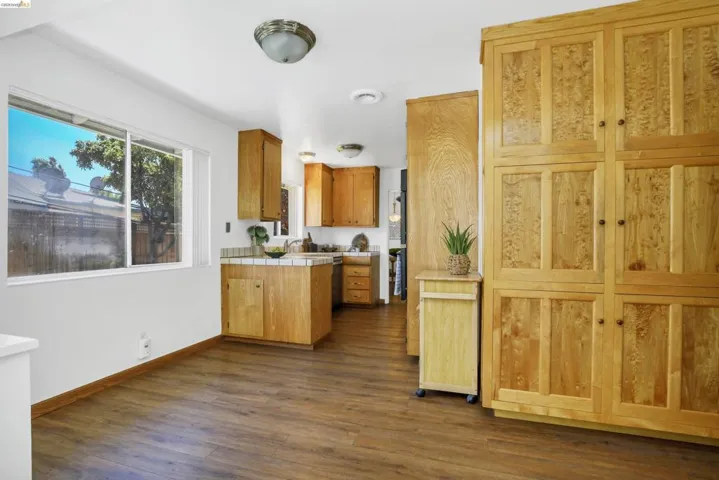 Kitchen area featuring extensive light-toned wood cabinetry and wood-finish flooring